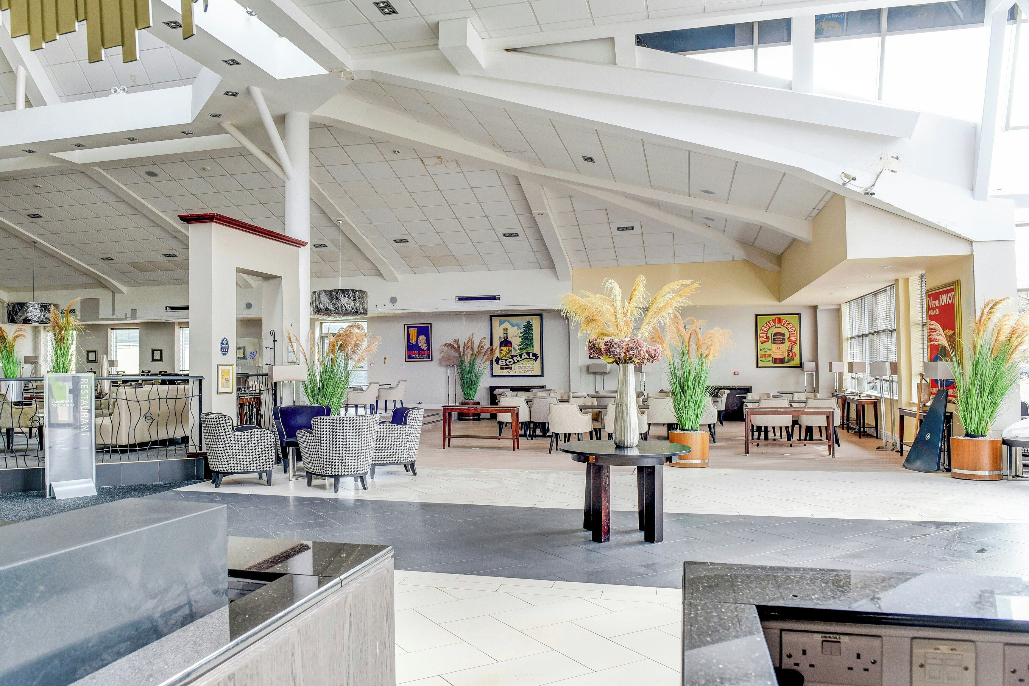 A spacious lobby with high ceilings, modern furniture, and decorative plants.