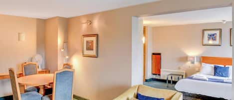 A hotel room with a bed, a desk, a chair, and a couch.