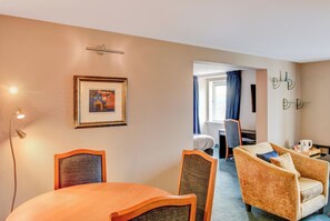 A hotel room with a dining table, two chairs, a sofa, a bed, a desk, and a window with curtains. - Belvilla Aberdeen Bridge Of Don Exhibition Centre (Aberdeen)