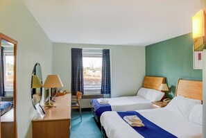 Une chambre d’hôtel avec deux lits, un bureau avec des lampes, une chaise et une fenêtre avec des rideaux.