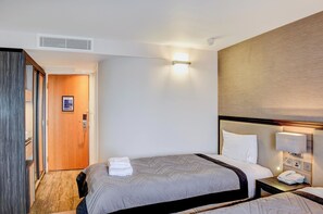 A hotel room with a bed, bedside table, lamp, and a wooden door. - Belvilla Aberdeen Bridge Of Don Exhibition Centre (Aberdeen)