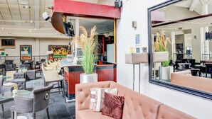 Un hall d’hôtel moderne comprenant un espace salon, un comptoir d’accueil et un grand miroir qui reflète l’intérieur.