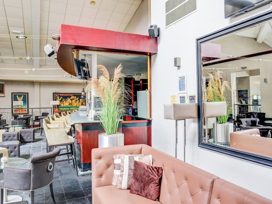Un moderno vestíbulo de hotel con zona de estar, mostrador de recepción y un gran espejo que refleja el interior.
