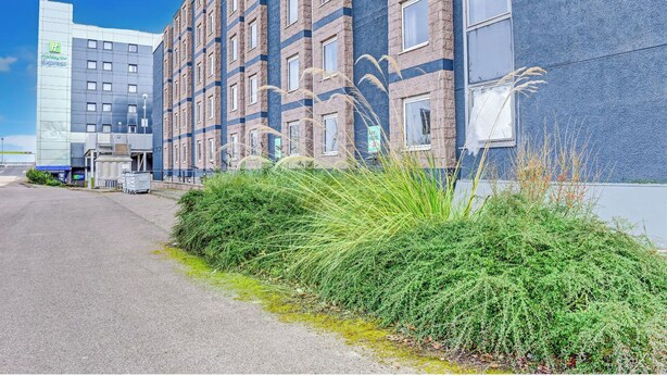 Un hôtel doté d’une façade moderne, d’une entrée bien visible et d’un espace paysager agrémenté de verdure.