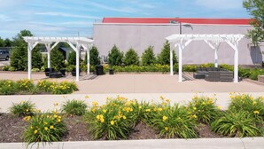A covered outdoor area with white pergolas, seating, and yellow flowers.
