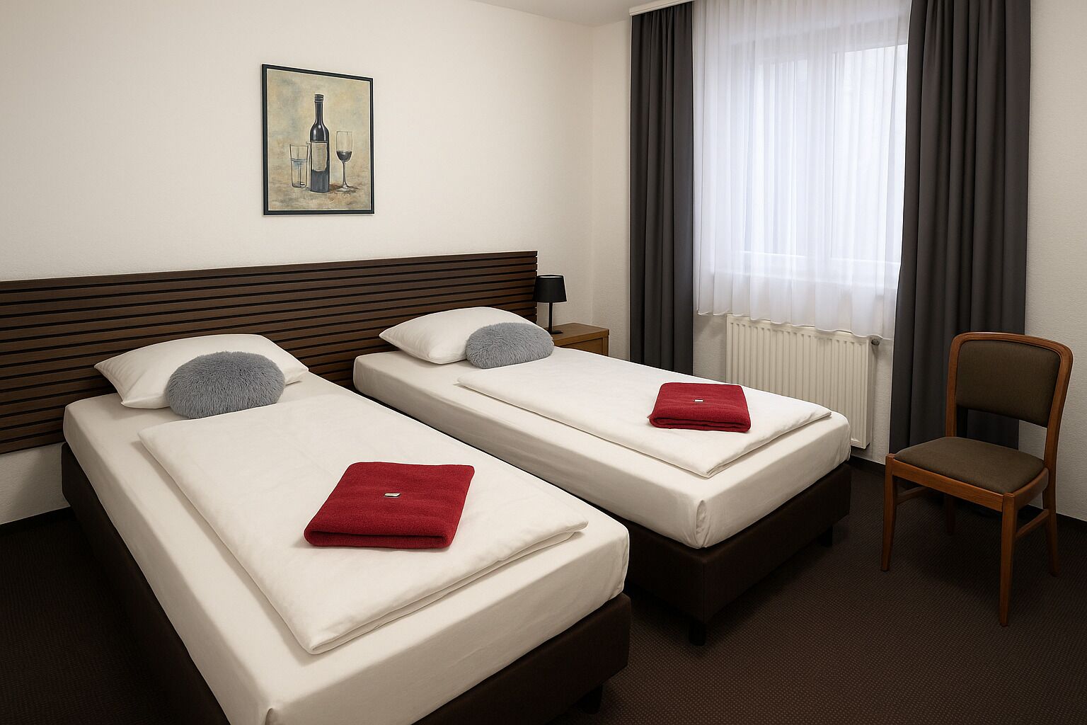 A hotel room with two beds, a wooden headboard, a red towel on each bed, a chair, a painting on the wall, and a window with curtains.