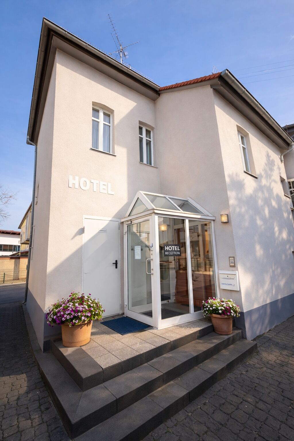 Et hotel med reception, glasdør og potteplanter.