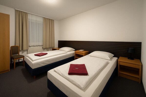 A hotel room with two single beds, a wooden nightstand, a desk, and a chair. - Nassauer Hof (Frankfurt)