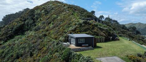 A modern house on a hillside with a small deck and a hot tub.