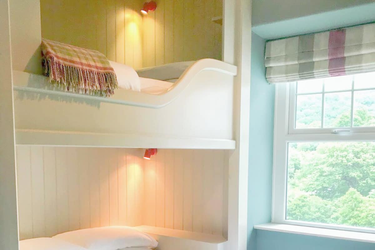 A bunk bed room with a window and a view of greenery outside.