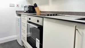 Ett modernt kök med vita skåp, en mikrovågsugn, ett knivställ och en spis.