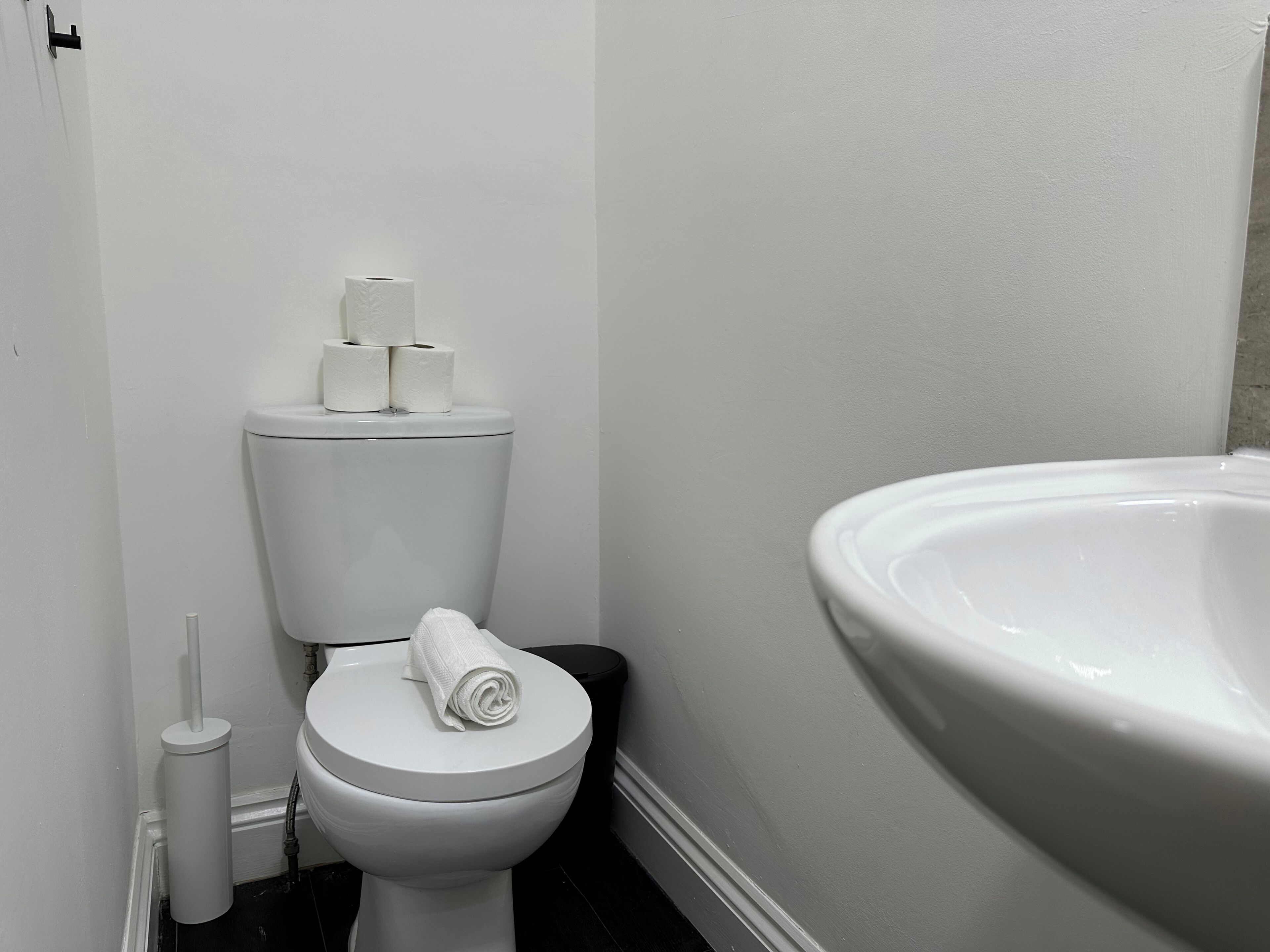 A bathroom with a toilet, a roll of toilet paper, a towel, and a large bathtub.