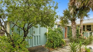 A garden with a wooden deck, a palm tree, and a house with a green door. - 1267 S Fletcher ~ 4 BR House, Walk to the Beach! (Fernandina Beach)
