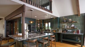 A modern kitchen with a large island, bar stools, and a mezzanine level. - Hidden Homestead: 5 acres, Luxe Cabin, Sauna, Dome, Gym (Bailey)