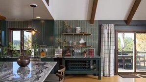 A modern kitchen with a marble countertop, wooden chairs, and a built-in wine rack. - Hidden Homestead: 5 acres, Luxe Cabin, Sauna, Dome, Gym (Bailey)