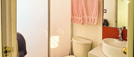 A compact bathroom with a toilet, sink, and shower.