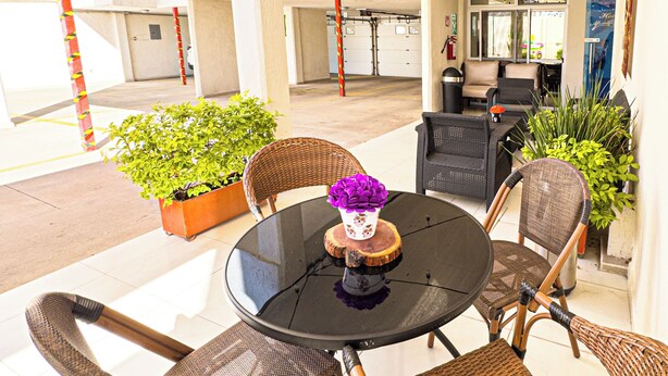 An outdoor patio area with wicker chairs, a round table, and string lights. - Hotel Montecarlo (San Luis Potosí)