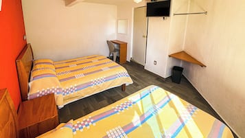 Una habitación con dos camas, ventilador de techo, televisión montada en la pared y un escritorio pequeño.