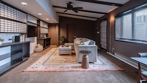 Uma sala de estar moderna com um sofá cinzento, uma mesa de centro e um ventilador de teto.