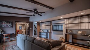 Uma sala de estar moderna com um sofá seccional cinza, uma mesa de centro de madeira e um tapete estampado.