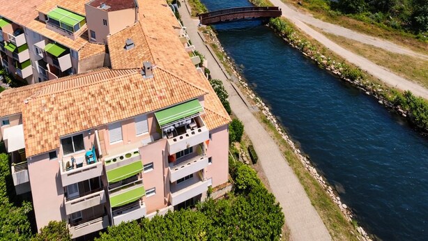 A coastal town with a river, a bridge, and a swimming pool area. - Apartment lake salonique (Le Grau-du-Roi)