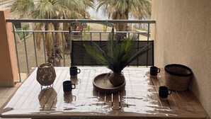A balcony with a table, chairs, a potted plant, and a water container. - Apartment lake salonique (Le Grau-du-Roi)