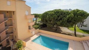 A residential building with a swimming pool, balconies, and a tree-lined courtyard. - Apartment lake salonique (Le Grau-du-Roi)