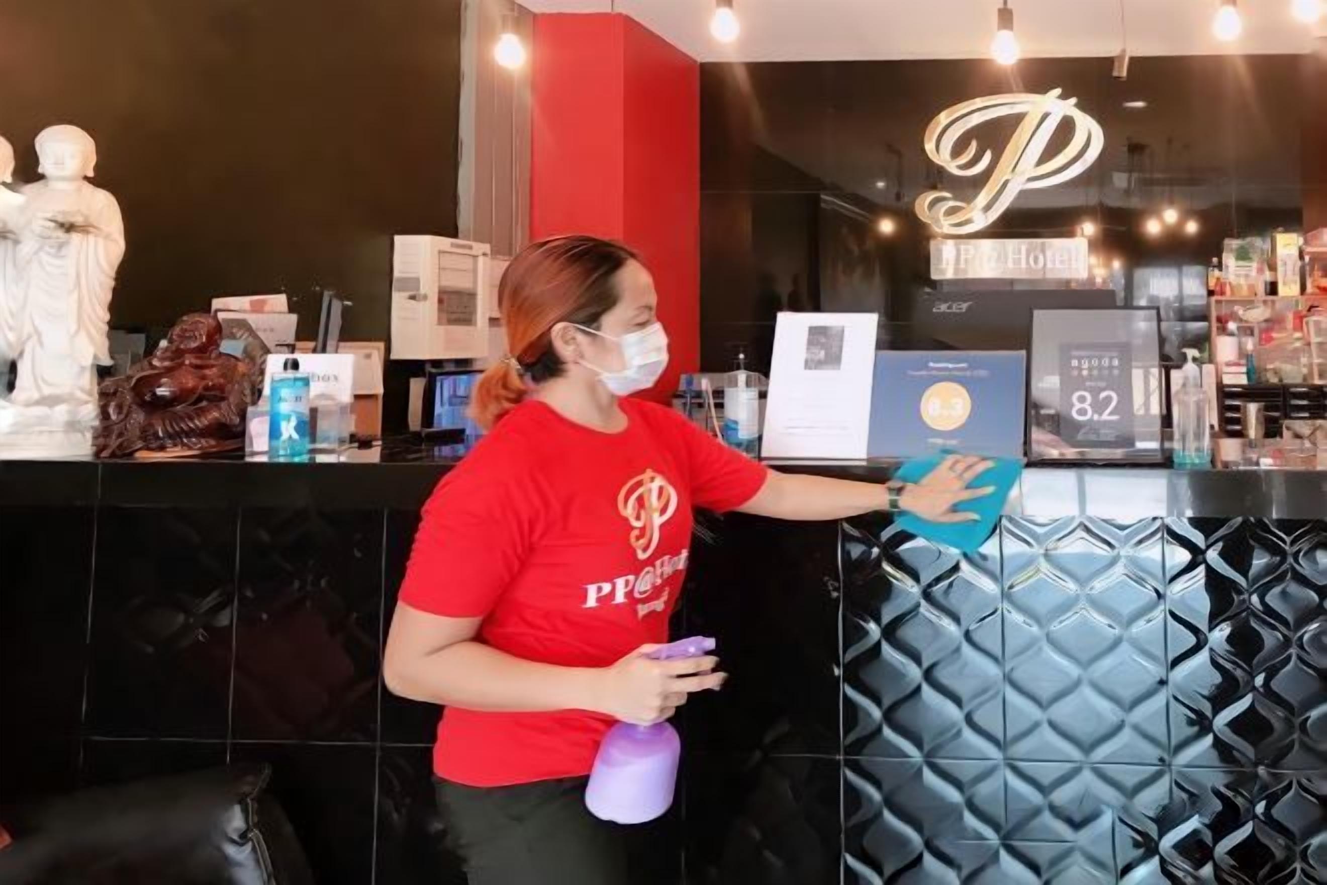 A person cleaning a black, textured wall in a hotel lobby.