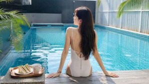 Eine Person sitzt am Pool und hält eine Serviertablett mit Essen.