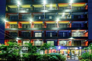 Ein mehrstöckiges Hotel mit Balkonen, einem gut sichtbaren Eingang und einer hell erleuchteten Fassade.