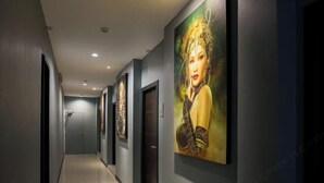 Ein Korridor mit dunklen Wänden und Decke, der mehrere gerahmte Kunstwerke und Türen zeigt.
