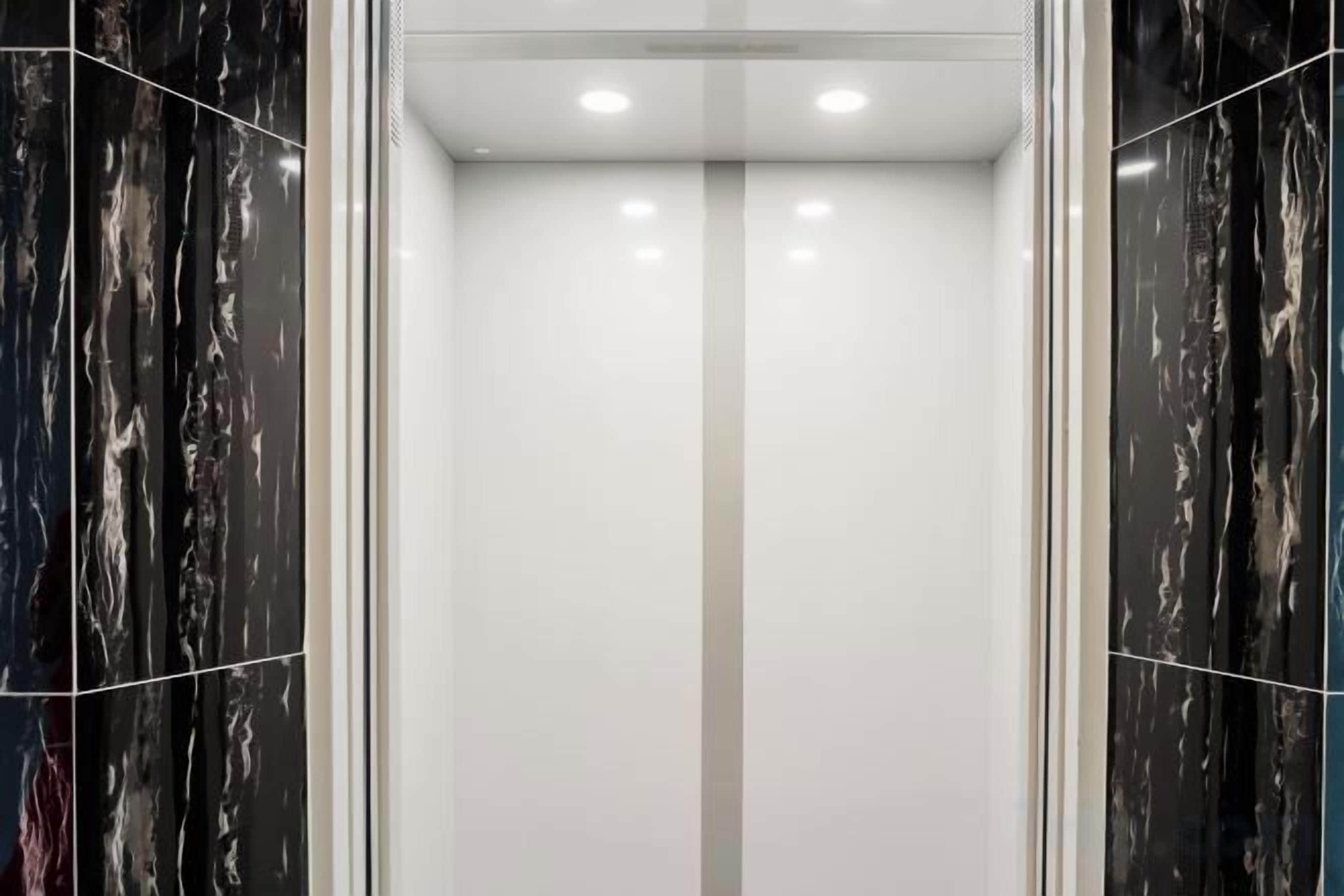 Un ascenseur doté d’un mur miroir et d’un luminaire central.