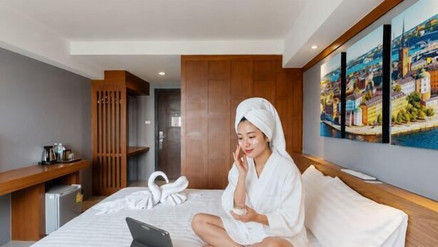 Ein Hotelzimmer mit einem Bett, einem Laptop, einer Flasche und einem Handtuch.