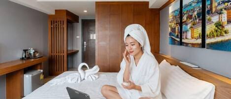Een hotelkamer met een bed, een laptop, een fles en een handdoek.