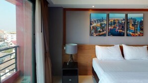 Ein Hotelzimmer mit Bett, Nachttisch mit Lampe und Stadtbild an der Wand.