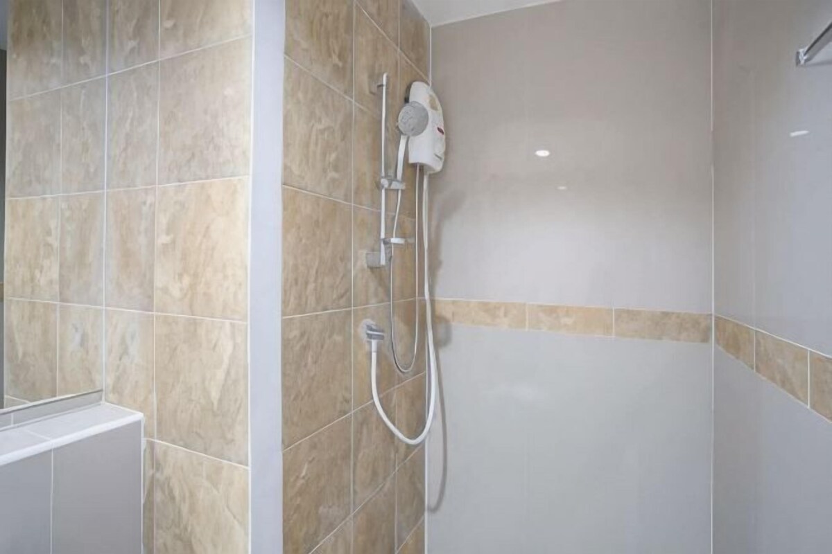 Une douche équipée d’un pommeau de douche à main et d’un robinet mural.