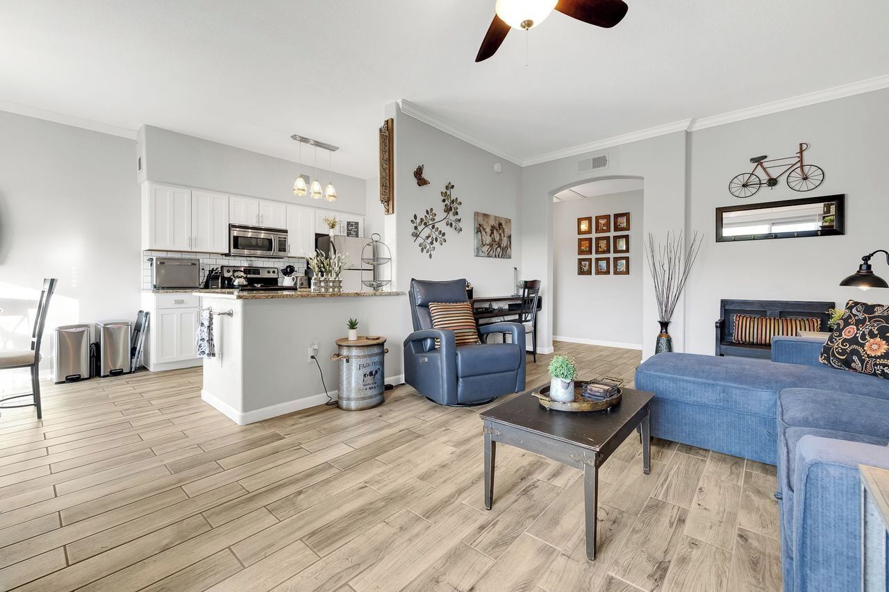 A modern kitchen with white cabinets, a central island, and a dining area with a blue sofa and a coffee table.