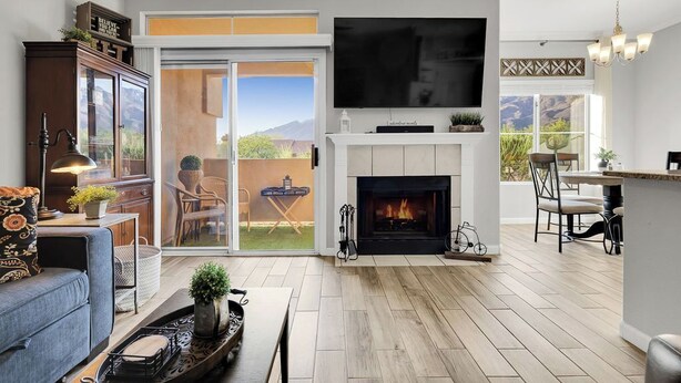 A living room with a fireplace, a television, and a sliding glass door leading to an outdoor patio. - Charming, Clean, Condo with 24 Hour_Gated Access, Spectacular Catalina Mtn Views (Tucson)