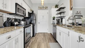 A kitchen with white cabinets, a black refrigerator, stainless steel appliances, and a wooden floor. - Charming, Clean, Condo with 24 Hour_Gated Access, Spectacular Catalina Mtn Views (Tucson)