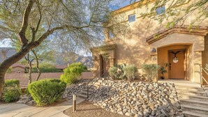 A building with a stone staircase, a door with a sign, and a tree. - Charming, Clean, Condo with 24 Hour_Gated Access, Spectacular Catalina Mtn Views (Tucson)