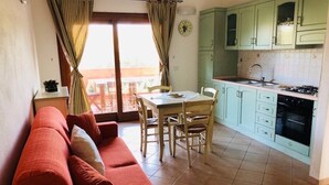 Un soggiorno con divano, un tavolo da pranzo con sedie e una cucina con pensili e piano cottura.