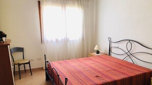 Una camera da letto con un letto, una sedia, una scrivania e una lampada.