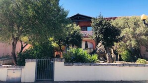 Un edificio tradizionale con tetto rosso, immerso nel verde e circondato da un muro in pietra.