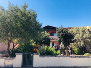 A traditional building with a red roof, surrounded by lush greenery and a stone wall. - Three-room apartment I Graniti a few minutes beaches Marine Park Tavolara (Monte Petrosu)