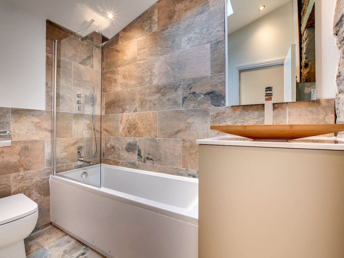 Un bagno moderno con una vasca da bagno freestanding, una cabina doccia in vetro e un grande specchio sopra il lavabo.