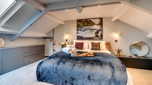 A modern bedroom with a large bed, a skylight, a painting of a waterfall, and a nightstand with a mirror. - Aysgarth Nook by Luxury Travel Emporium (Aysgarth)