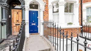 Une ruelle étroite avec une porte bleue, une porte en bois et une fenêtre blanche avec des volets.