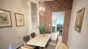 A dining area with a wooden table, cushioned chairs, and a hanging light fixture.