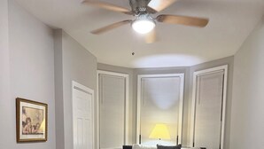 A bedroom with a bed, a ceiling fan, and a window with blinds.