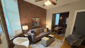 A living room with a brick wall, a sofa, a coffee table, and a ceiling fan.
